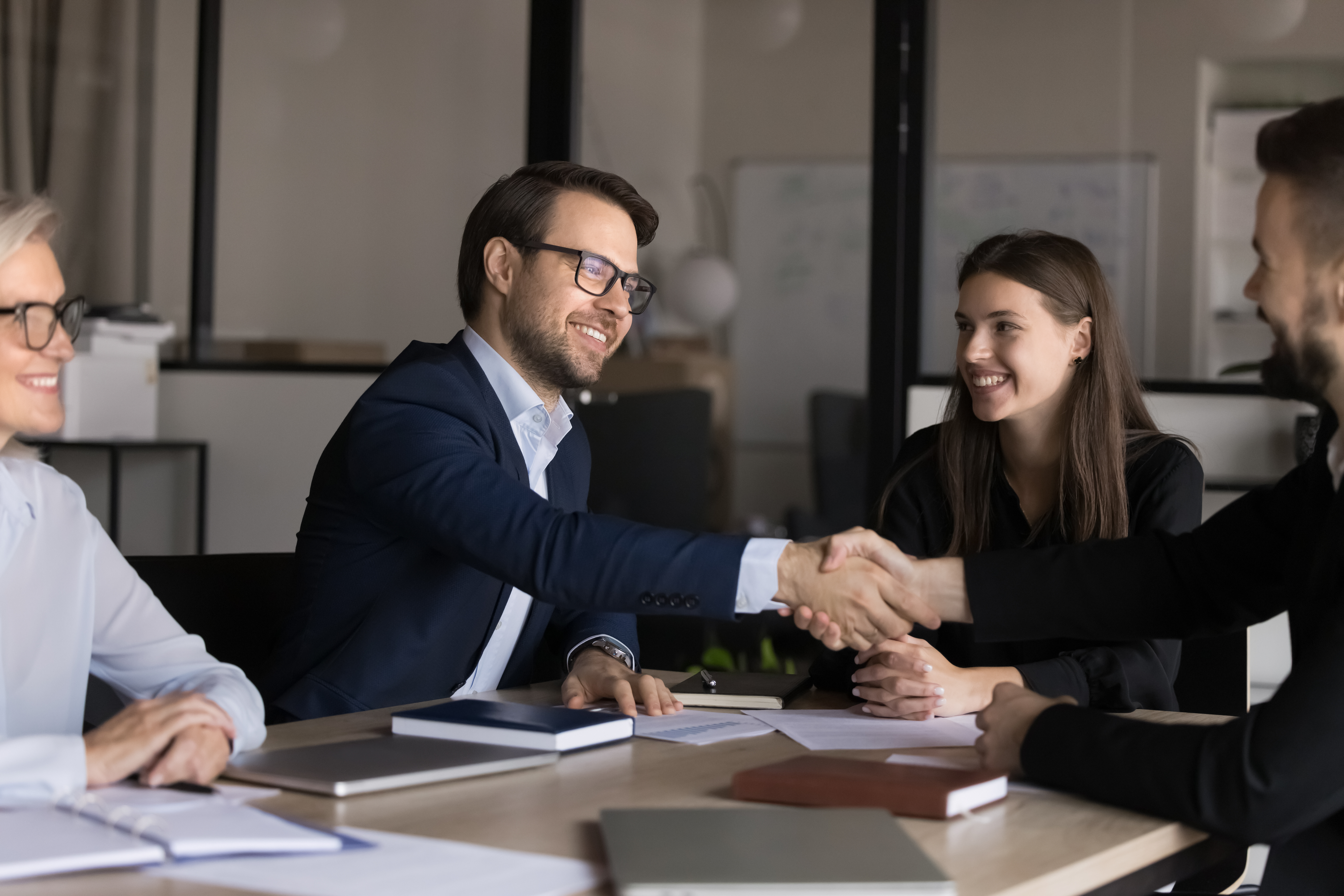 Smiling male colleagues, shareholders shake hands close deal at meeting